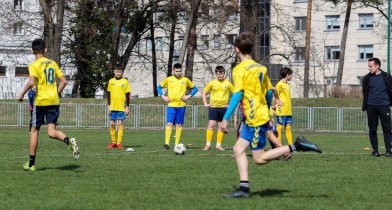 Grupa chłopców grająca w piłkę nożną na boisku. - powiększ